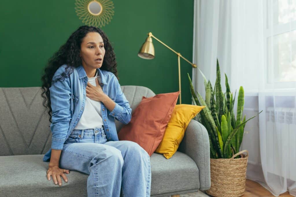 Woman having panic attack, Hispanic woman with curly hair alone at home depressed, having trouble