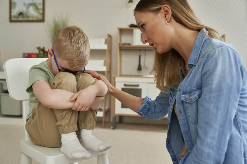 Sad little boy and therapist consoling him
